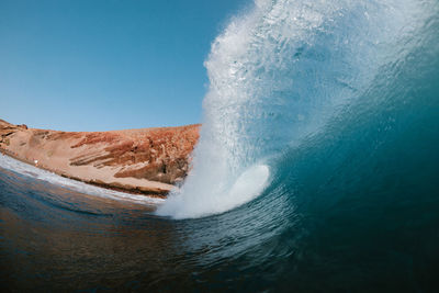 Blue wave breaking front a red mountain in tenerife