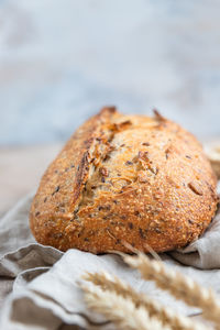 Loaf of artisan sourdough bread with wheat ears and linen napkin. tartine with multigrain seeds.