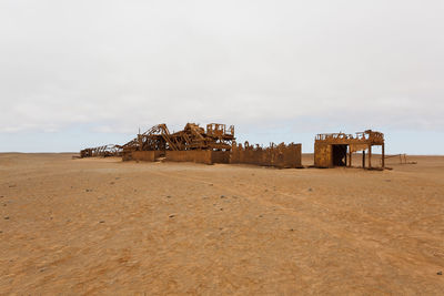 Abandoned structure on sand at beach against sky