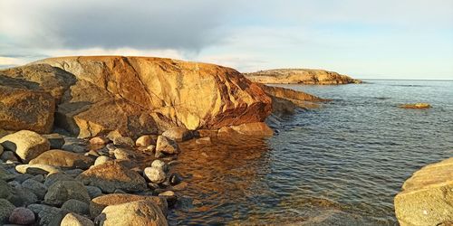 Scenic view of rocks on shore against sky