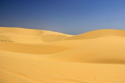 View of calm desert against clear blue sky