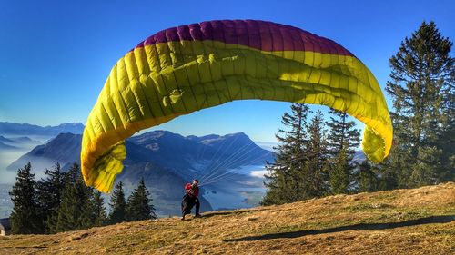 Man paragliding on mountain against blue sky