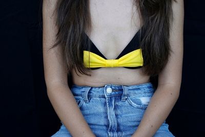 Midsection of woman sitting against black background