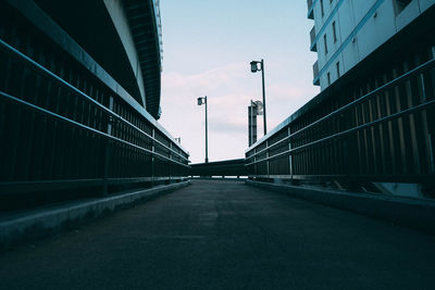 Empty road amidst buildings against sky in city