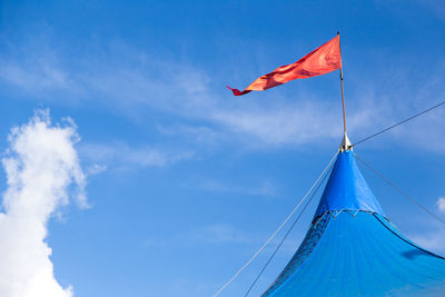 Low angle view of festival tent flag against blue sky