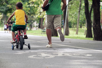 Rear view of men riding bicycle on road