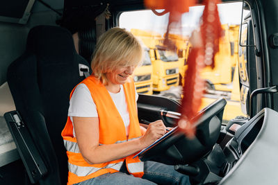 Smiling driver writing sitting in truck