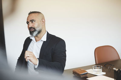 Confident male lawyer talking while looking away at conference table in board room