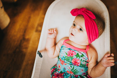 High angle view of baby wearing bandana sitting in bouncer chair 