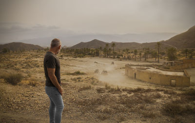 Adult man in tabernas desert, almeria, spain, with an abandoned village in summer