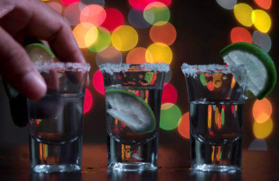 Cropped image of hand picking tequila shot at bar