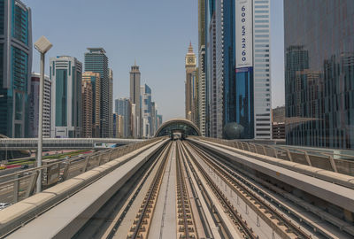 Railroad tracks amidst buildings in city against clear sky