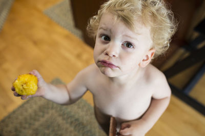 Guilty looking young toddler holds up a half eaten peach
