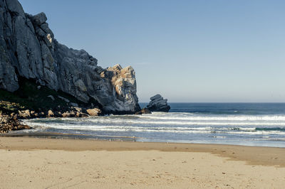 Rock formation on beach against clear sky