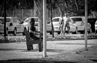 Side view of woman sitting on bench at park