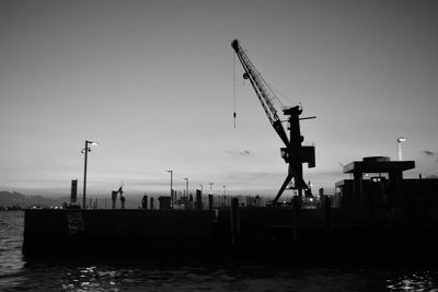 Cranes at commercial dock against clear sky