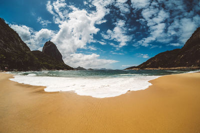 View of calm beach against cloudy sky