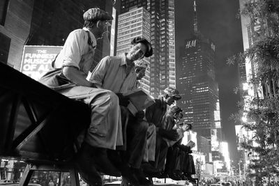 Low angle view of people sitting in city at night