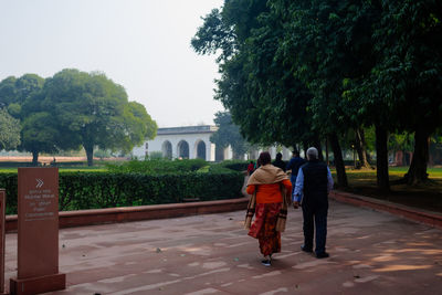 Rear view of man and woman walking against trees