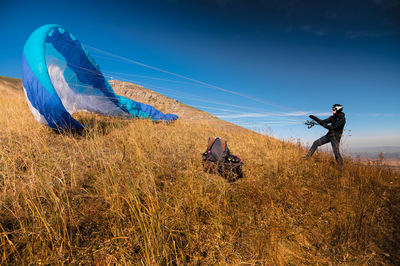 The paraglider is preparing to take off. a colorful kite lies on the grass, in the background there