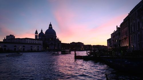 Canal amidst buildings against sky at sunset