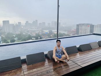 Full length of man sitting on floor against buildings in city