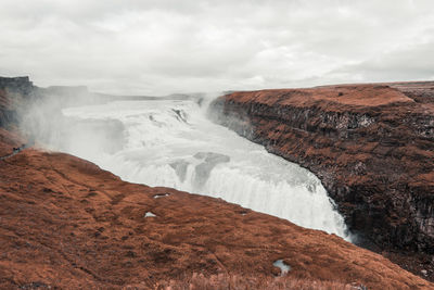 Scenic view of waterfall against sky