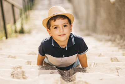 High angle portrait of cute boy wearing hat lying on steps