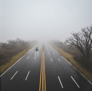 Foggy road with single car