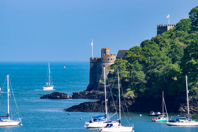 Sailboats in sea against blue sky