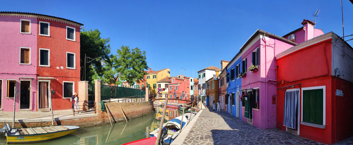 Houses by canal against sky in city