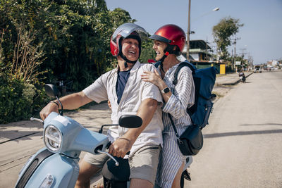 Happy senior man enjoying road trip with woman on scooter