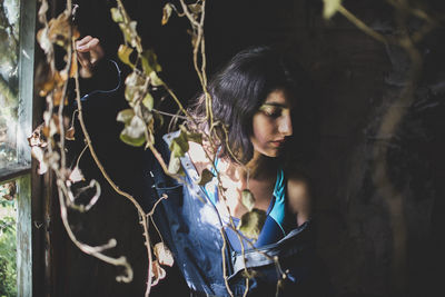 Woman looking away standing by plant