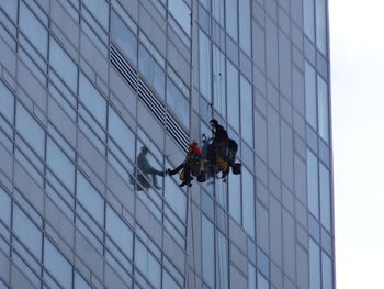 Low angle view of window washers on building