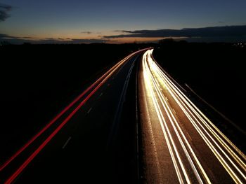 Light trails on road against sky at night