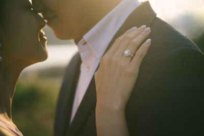 Close-up of newlywed couple romancing while standing outdoors during sunset