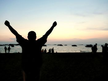 Silhouette people standing on beach against sky during sunset