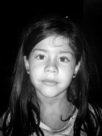 Close-up portrait of cute girl with long hair against black background