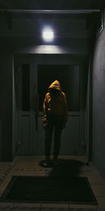 Man wearing hooded shirt standing in illuminated room