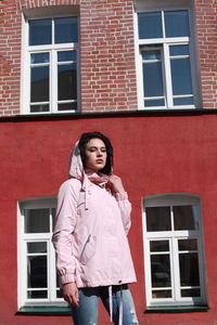 Young woman standing against red building