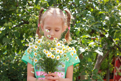 Girl with blond hair in pigtails with a bouquet of daisies. bouquet to mom, grandmother for holiday