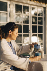 Mature woman pouring coffee at table in holiday villa