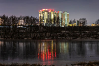 High-rise building on the bank of the river uvod and its reflection on the mirror ice surface russia