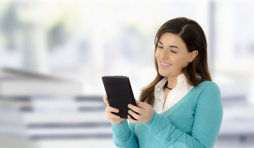 Woman smiling while using digital tablet