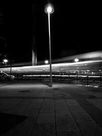 Illuminated street lights against sky at night