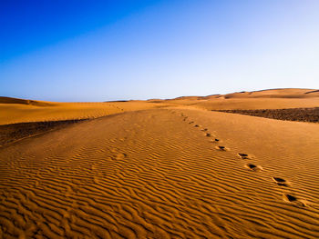 Scenic view of desert against clear blue sky