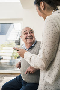 Senior man smiling at nurse with stethoscope at home