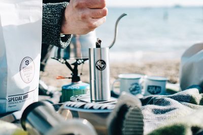 Close-up of hands on table by sea