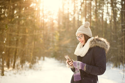 Young woman using mobile phone on snow covered field