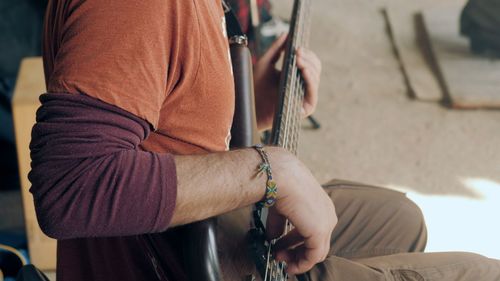 Midsection of man playing with guitar outdoors